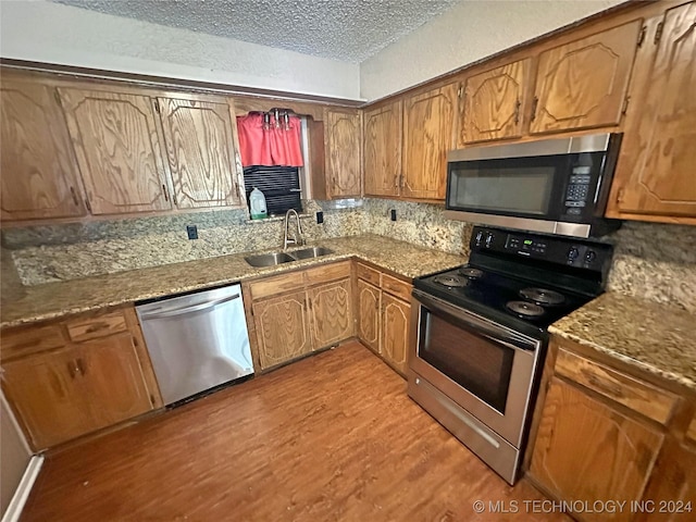 kitchen with tasteful backsplash, sink, light wood-type flooring, and appliances with stainless steel finishes