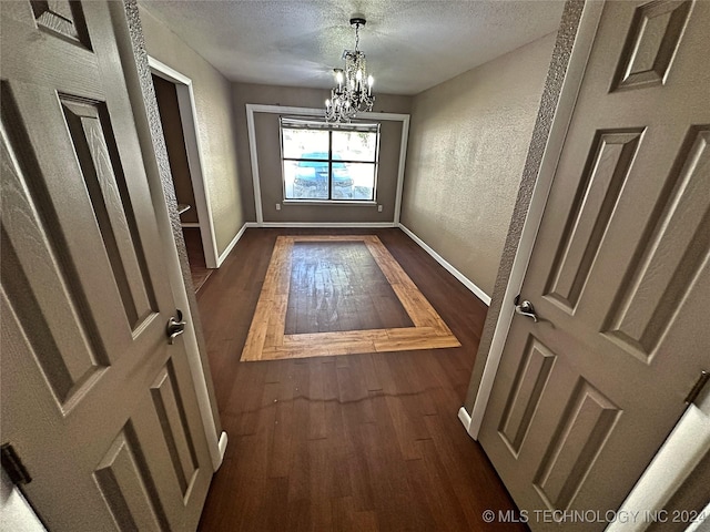 doorway to outside featuring dark wood-type flooring, an inviting chandelier, and a textured ceiling