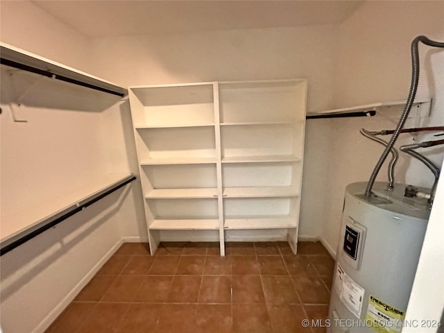 walk in closet featuring dark tile patterned floors and electric water heater