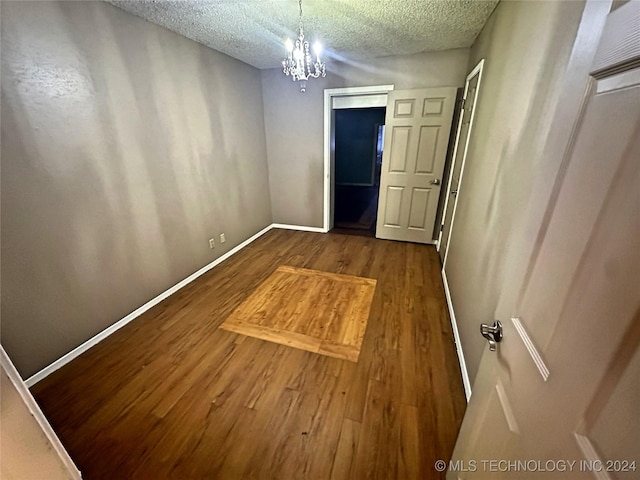 unfurnished bedroom featuring an inviting chandelier, hardwood / wood-style floors, and a textured ceiling