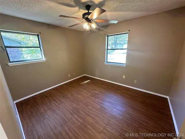 empty room with ceiling fan, dark wood-type flooring, and a textured ceiling