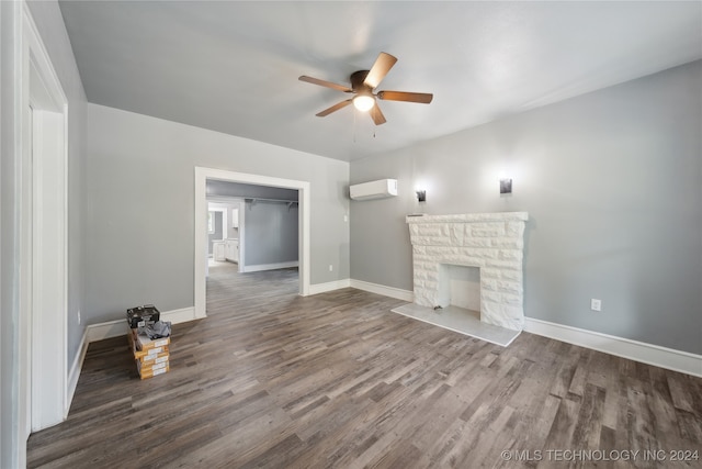 unfurnished living room with a wall mounted AC, a fireplace, dark hardwood / wood-style flooring, and ceiling fan