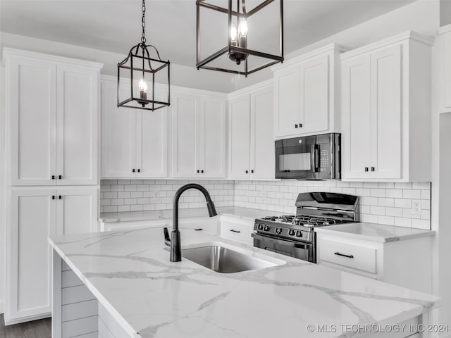 kitchen with light stone counters, stainless steel gas range oven, sink, pendant lighting, and white cabinetry