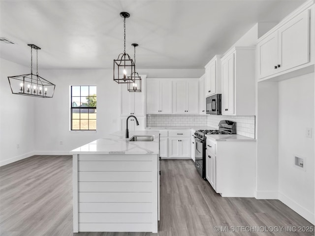 kitchen with black range with gas stovetop, white cabinetry, sink, and decorative light fixtures