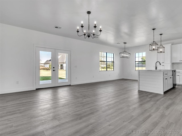 unfurnished living room featuring french doors, sink, and light hardwood / wood-style flooring