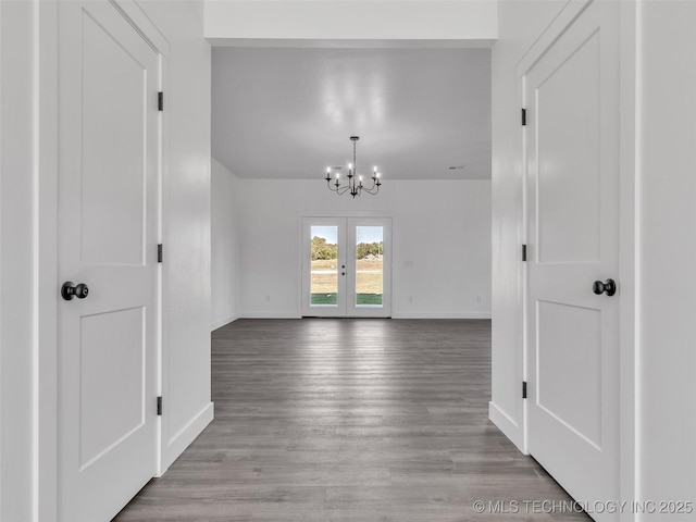 spare room featuring french doors, light hardwood / wood-style floors, and a notable chandelier