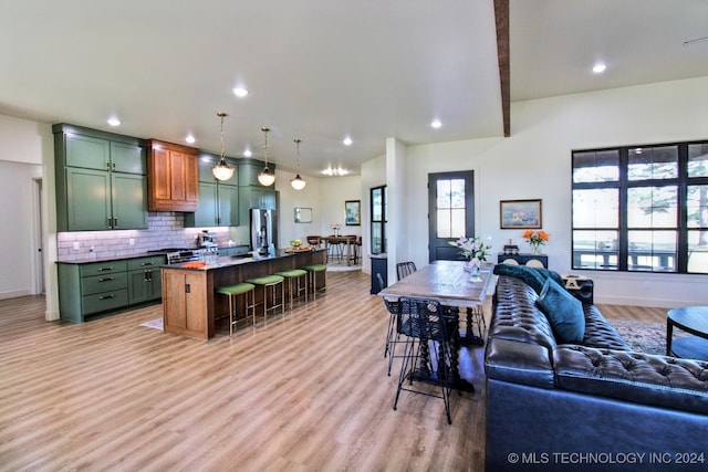 kitchen with green cabinets, a breakfast bar, hanging light fixtures, and a center island with sink