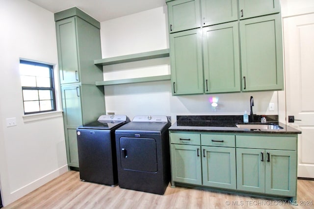 washroom featuring cabinets, sink, washer and dryer, and light wood-type flooring