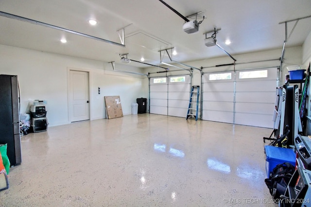 garage featuring a garage door opener and stainless steel refrigerator