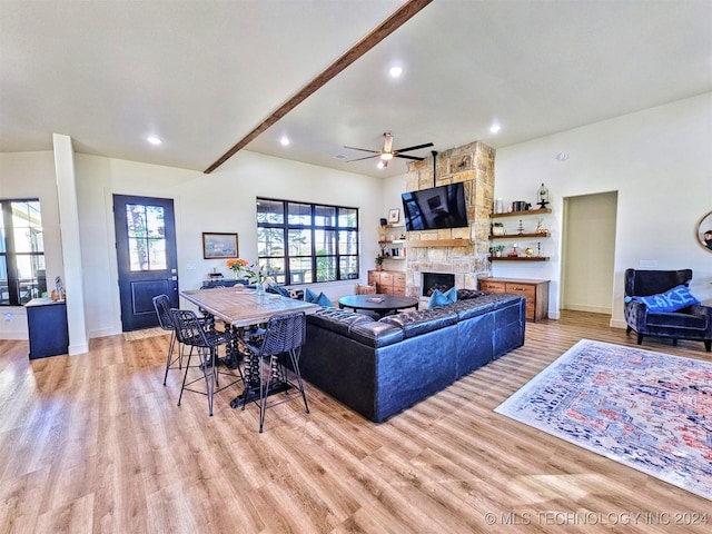 living room with beamed ceiling, a healthy amount of sunlight, a fireplace, and light wood-type flooring