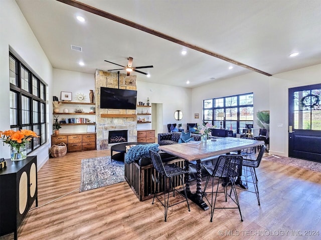 dining room with a fireplace, light hardwood / wood-style flooring, and ceiling fan