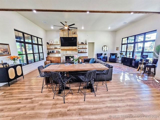 dining area featuring high vaulted ceiling, a fireplace, and light hardwood / wood-style floors