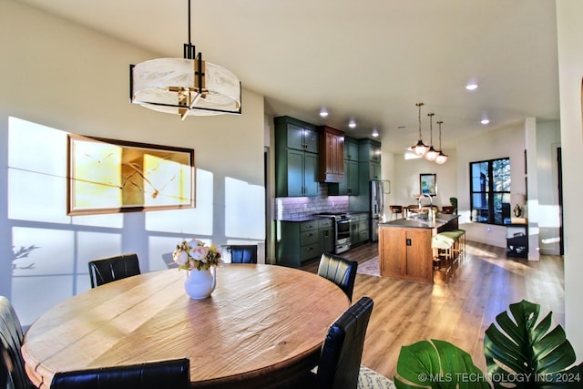 dining space featuring a chandelier, sink, and light hardwood / wood-style flooring