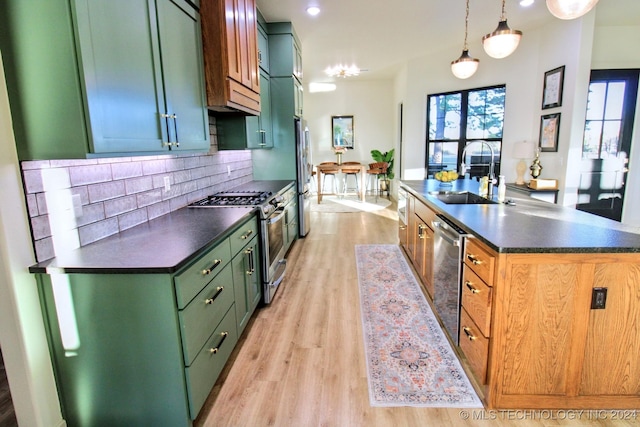 kitchen with sink, light hardwood / wood-style flooring, hanging light fixtures, appliances with stainless steel finishes, and backsplash