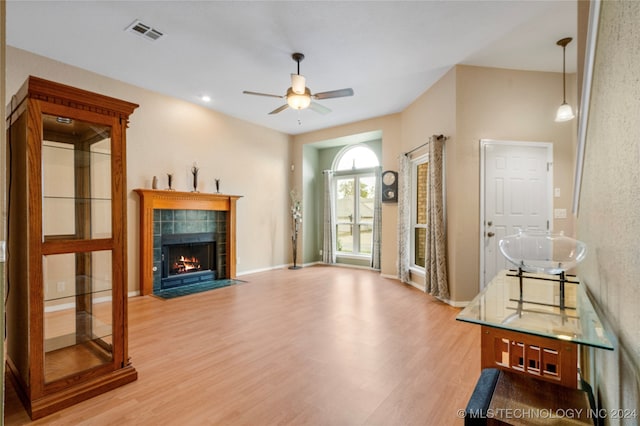 living room with a fireplace, ceiling fan, and light wood-type flooring