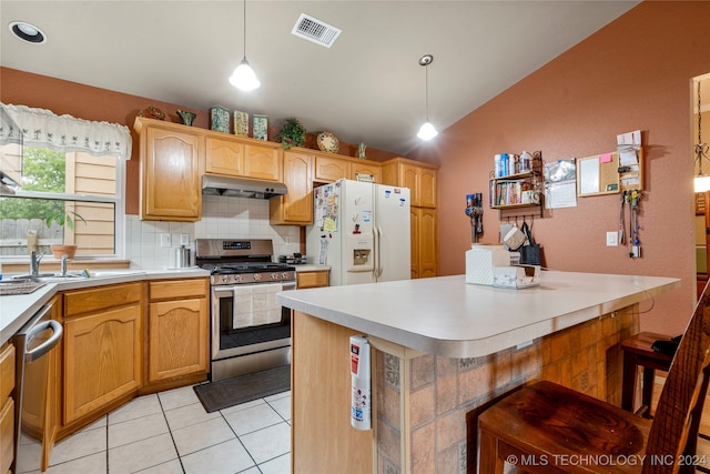 kitchen with appliances with stainless steel finishes, decorative light fixtures, light tile patterned floors, a breakfast bar area, and lofted ceiling