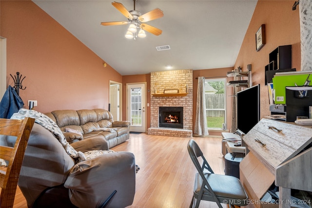 living room featuring light wood-type flooring, a fireplace, lofted ceiling, and ceiling fan