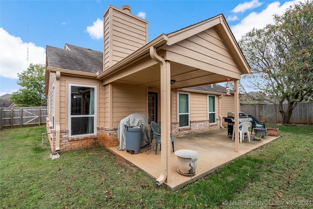 back of house with a patio area and a lawn