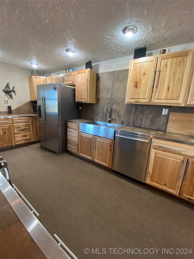 kitchen featuring sink, appliances with stainless steel finishes, a textured ceiling, and dark colored carpet