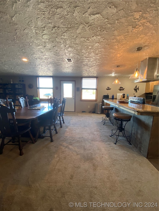 carpeted dining space with a textured ceiling