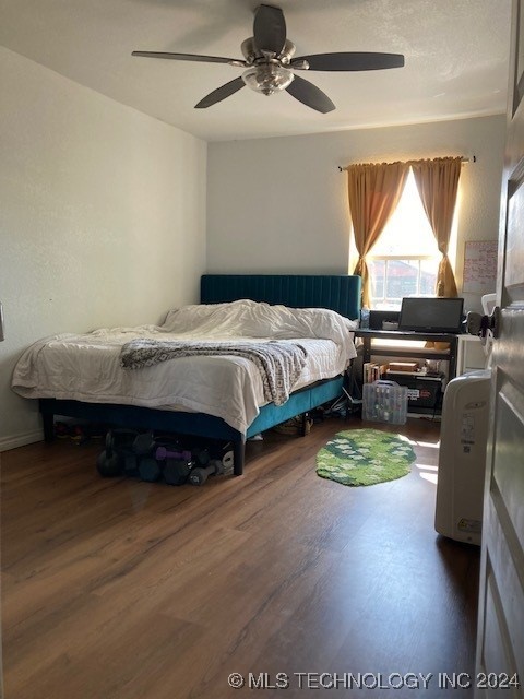 bedroom with dark hardwood / wood-style flooring and ceiling fan