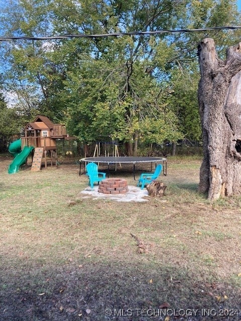 view of yard featuring a playground, a trampoline, and a fire pit