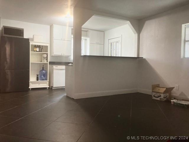 interior space featuring white dishwasher, white cabinetry, and dark tile patterned flooring