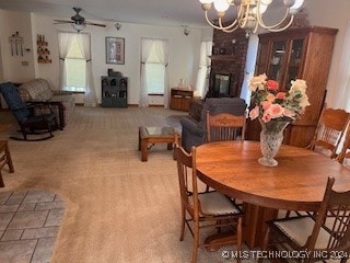 carpeted dining space with a brick fireplace and ceiling fan with notable chandelier