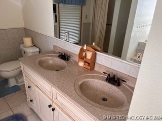 bathroom featuring toilet, vanity, tile walls, and tile patterned floors