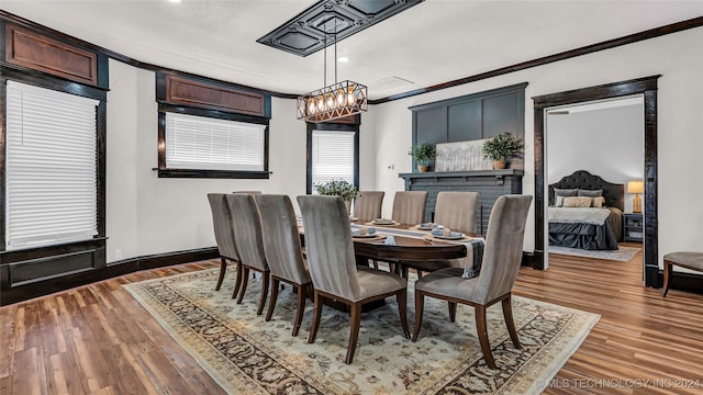 dining area with dark wood-type flooring, crown molding, and an inviting chandelier