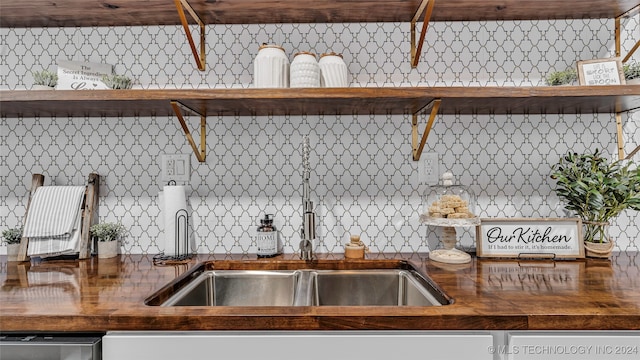 kitchen with stainless steel dishwasher, butcher block counters, sink, and decorative backsplash