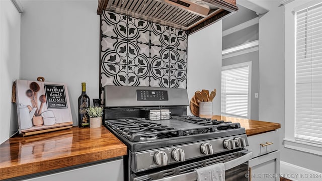 kitchen featuring ornamental molding, wooden counters, range hood, and stainless steel gas range