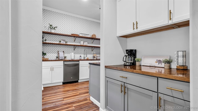 bar featuring tasteful backsplash, stainless steel dishwasher, crown molding, white cabinetry, and light hardwood / wood-style flooring