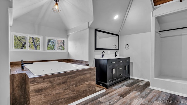 bathroom featuring hardwood / wood-style floors, a tub, vanity, and lofted ceiling