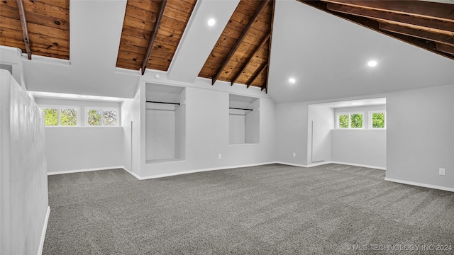 unfurnished living room with high vaulted ceiling, beamed ceiling, wood ceiling, and dark carpet