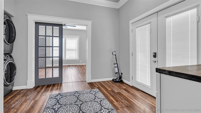 laundry room featuring stacked washer / dryer, dark wood-type flooring, french doors, and crown molding