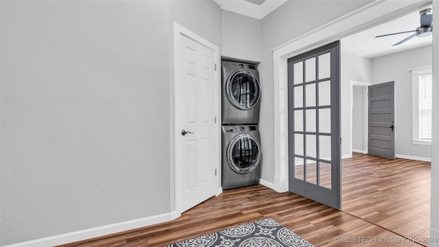 clothes washing area with crown molding, stacked washer and dryer, hardwood / wood-style flooring, and ceiling fan