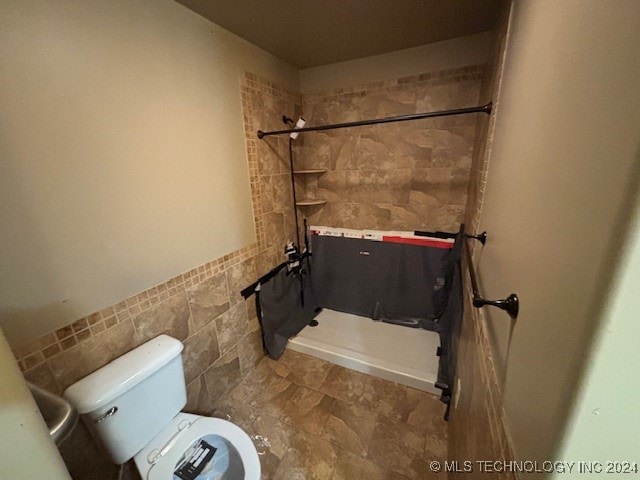 bathroom featuring a shower with curtain, toilet, and tile walls