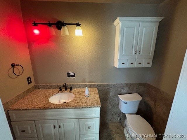 bathroom featuring tile walls, vanity, and toilet