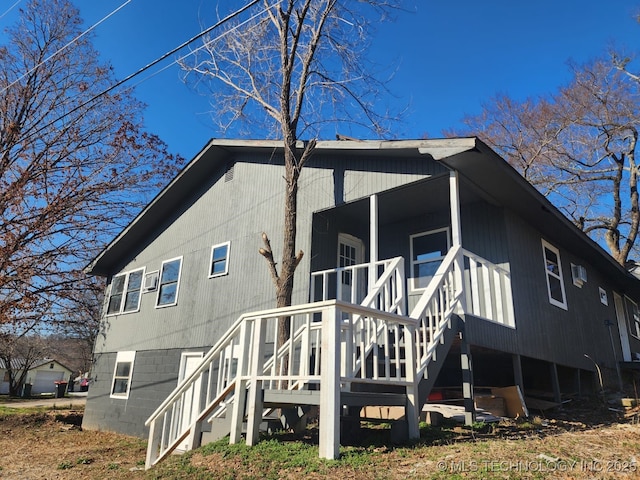 back of property with stairway and a porch