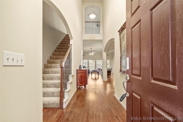 entryway with ceiling fan, hardwood / wood-style floors, and a high ceiling