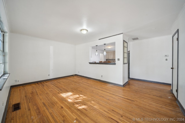 unfurnished living room featuring hardwood / wood-style flooring and crown molding