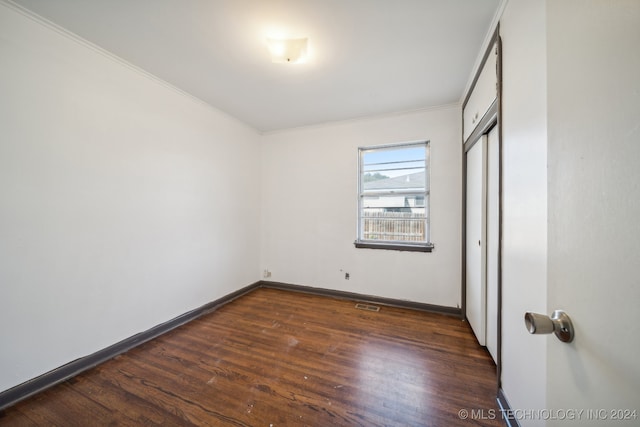 unfurnished bedroom with ornamental molding, dark hardwood / wood-style floors, and a closet