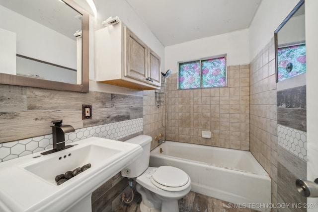 full bathroom with sink, tile walls, tiled shower / bath combo, tasteful backsplash, and toilet