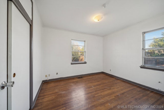 spare room with ornamental molding and dark hardwood / wood-style flooring