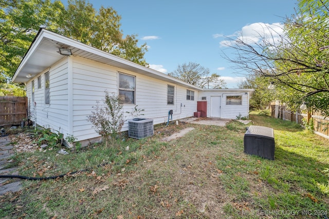 back of house featuring central AC unit and a yard