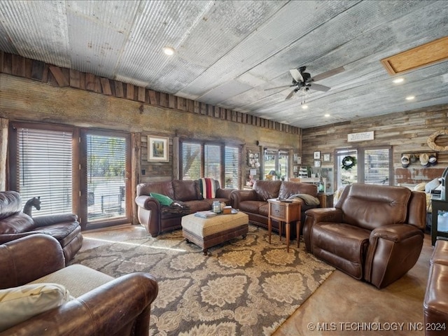 living room with a wealth of natural light, wood walls, and ceiling fan