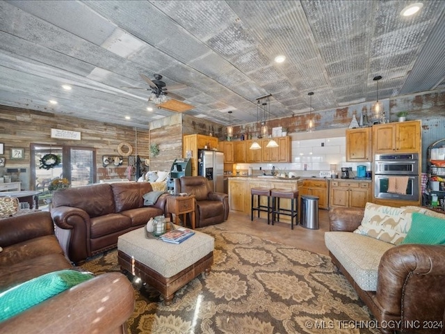 living room featuring concrete flooring, wood walls, and ceiling fan