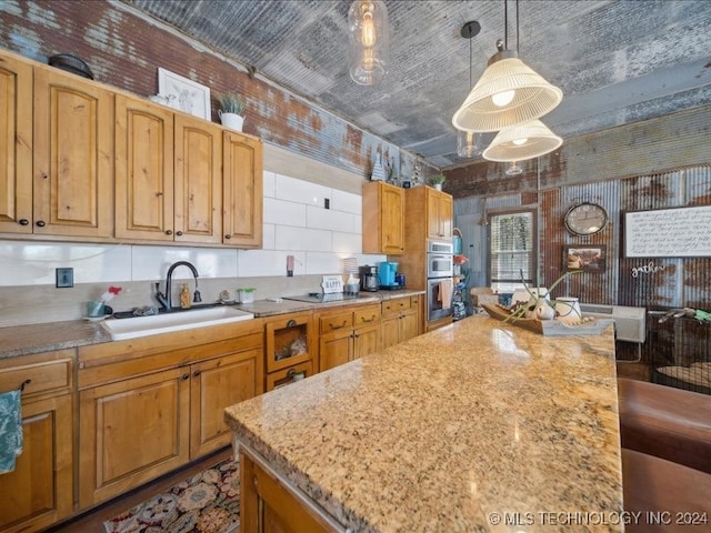 kitchen with hanging light fixtures, sink, double oven, and brick wall