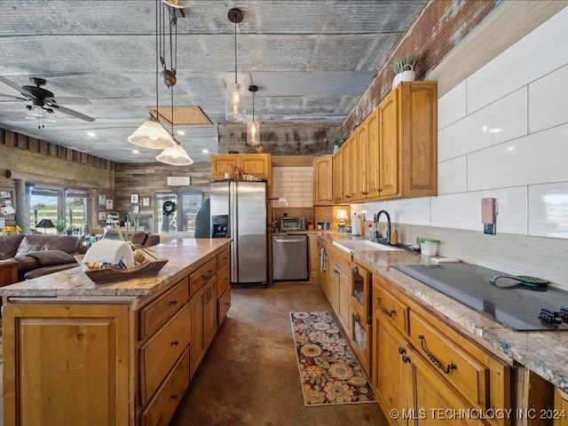 kitchen with stainless steel appliances, a center island, hanging light fixtures, sink, and light stone countertops